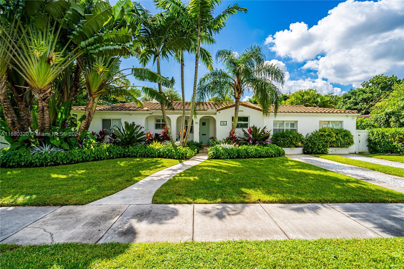 a view of a white house with a yard and potted plants