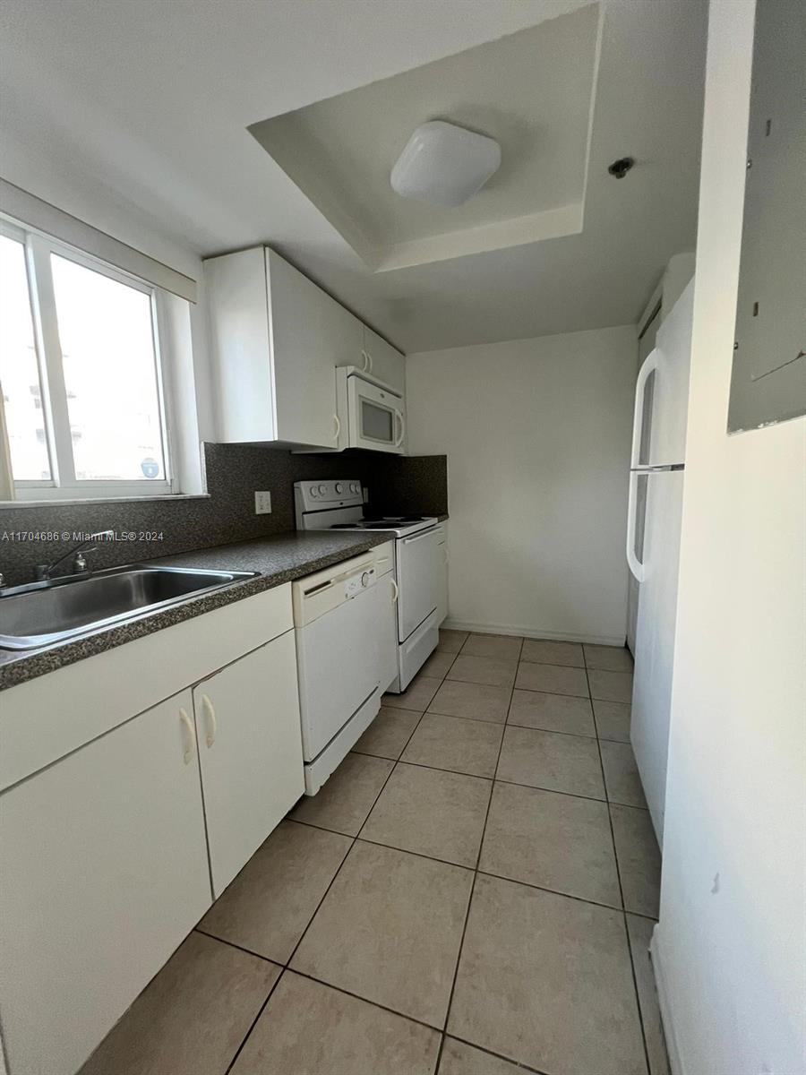 a kitchen with granite countertop a sink a stove and cabinets