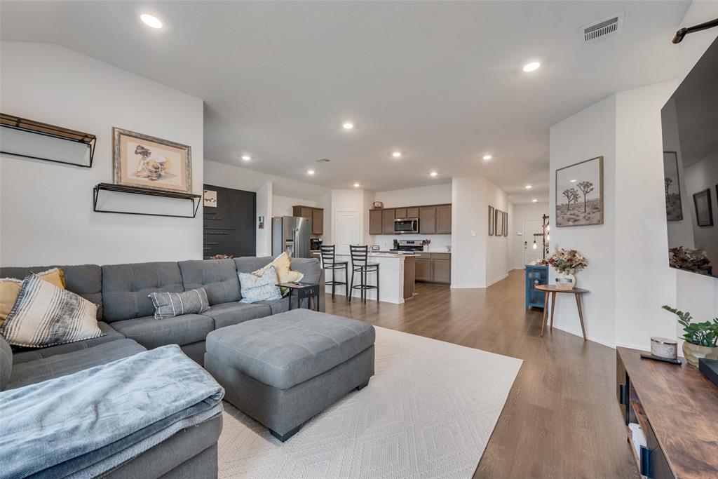 a living room with furniture wooden floor and a kitchen view