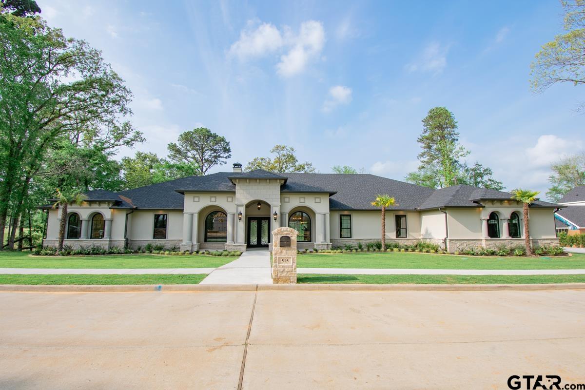 a front view of a house with a garden and trees