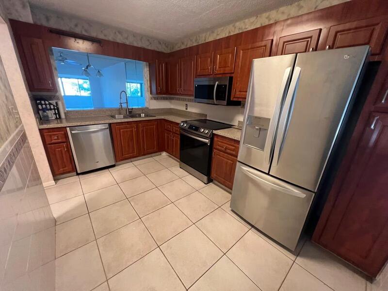 a kitchen with granite countertop a refrigerator sink and cabinets