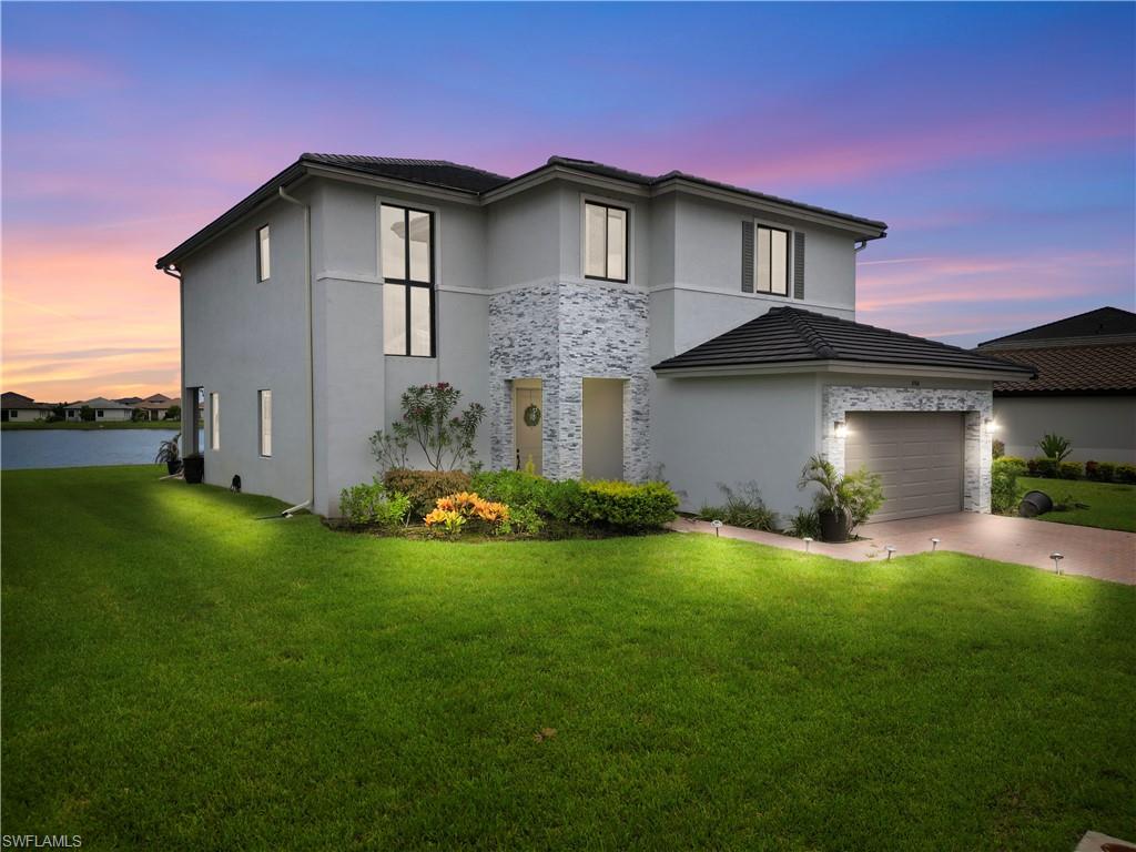 View of front facade featuring a garage and a yard