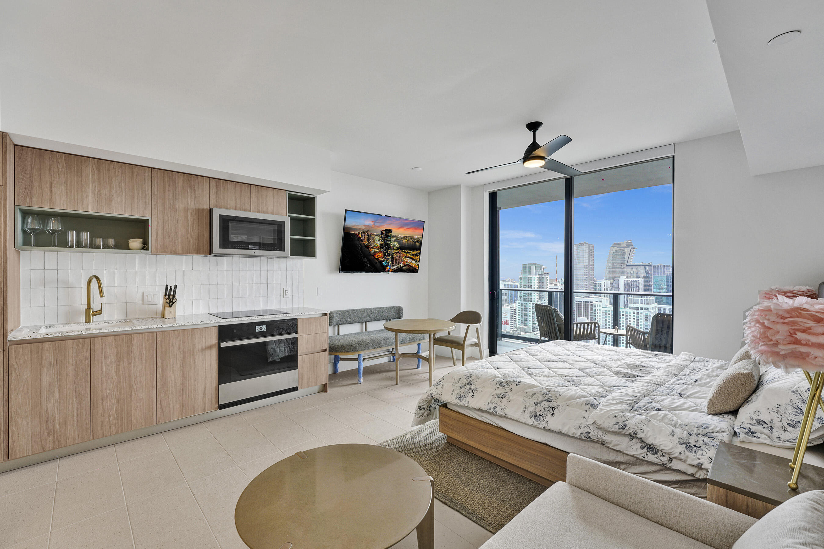 a living room with stainless steel appliances granite countertop furniture a fireplace a flat screen tv and a faucet