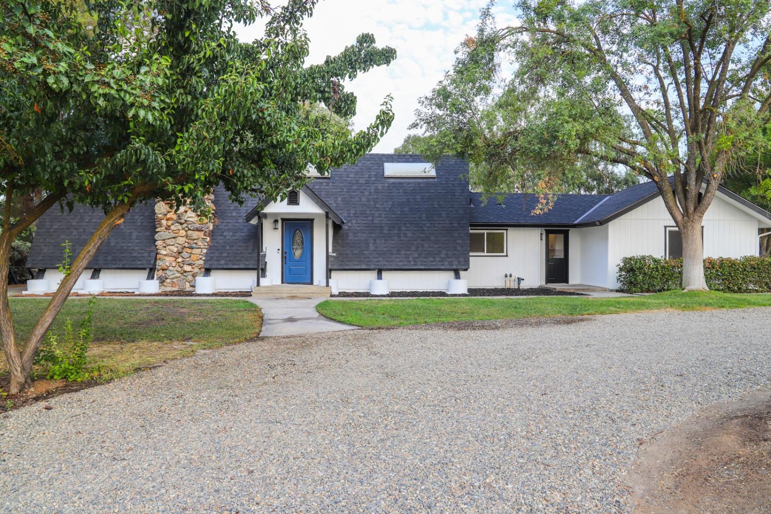 front view of house with a yard and an trees