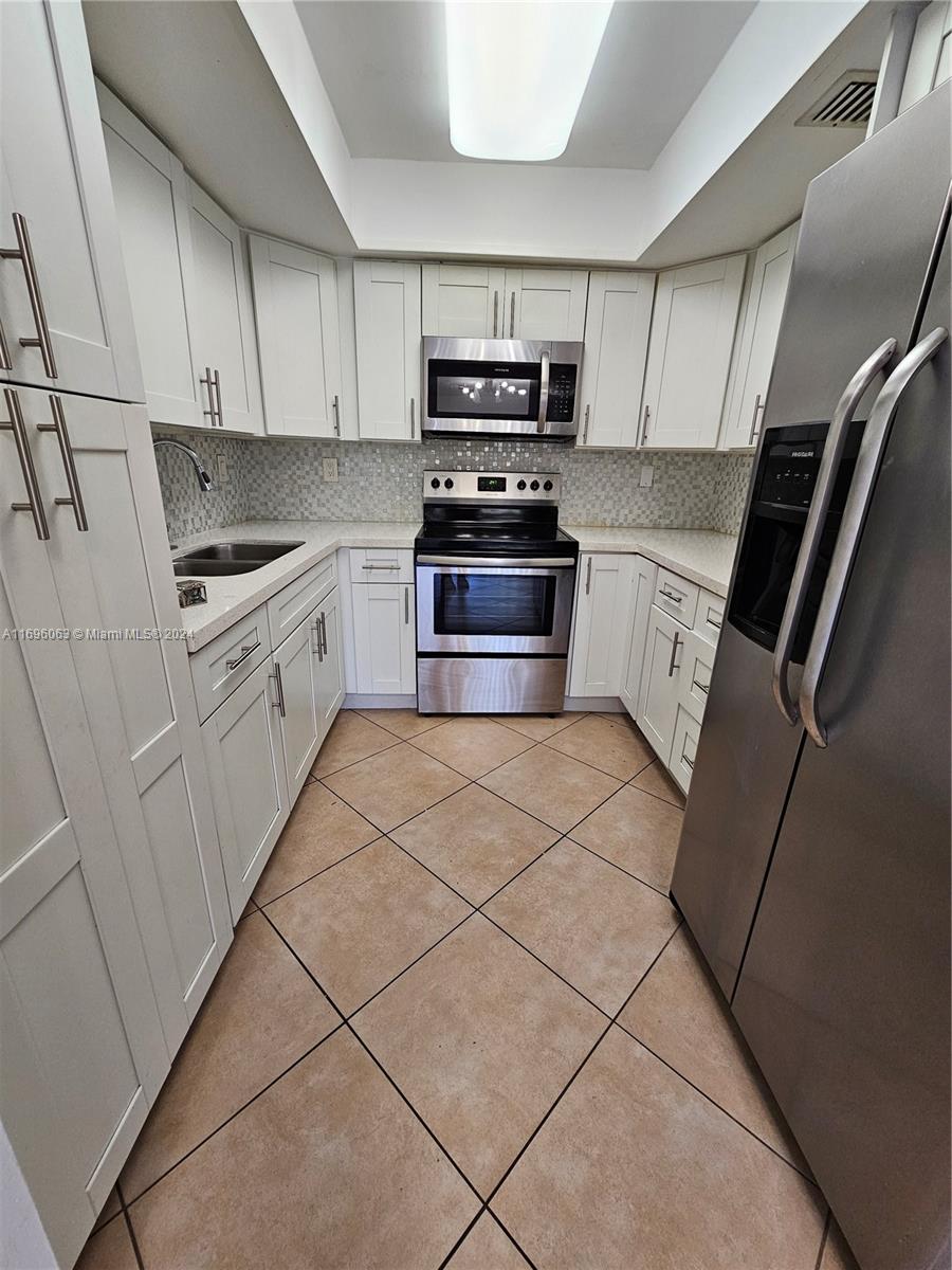 a kitchen with granite countertop a refrigerator and a stove top oven