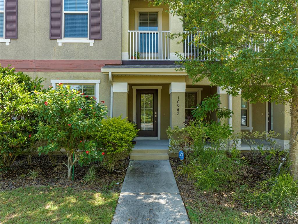 front view of front of house with potted plants and large trees