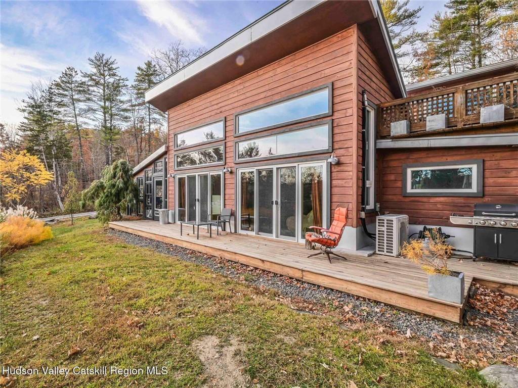 Back of house with a wooden deck and a lawn