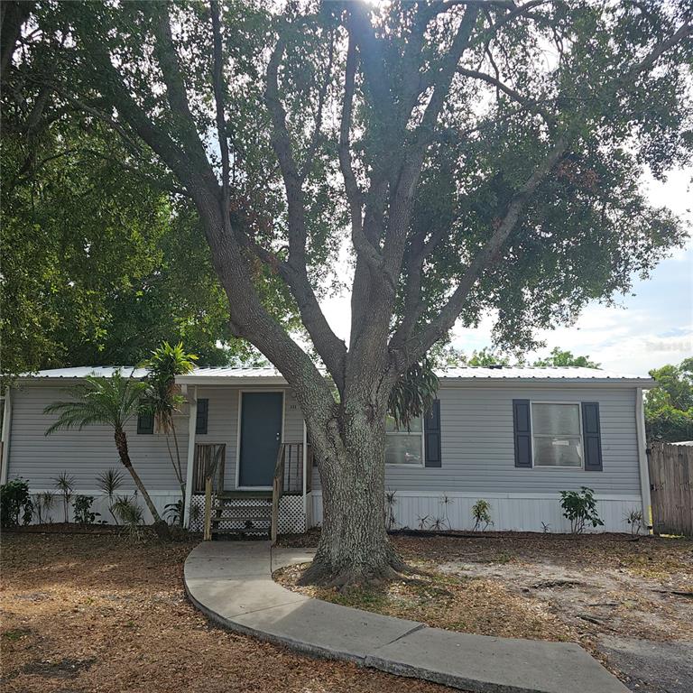 a view of a house with a yard and large tree