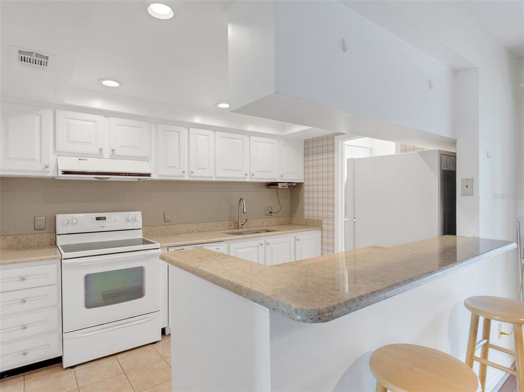 a kitchen with granite countertop a sink a stove and cabinets