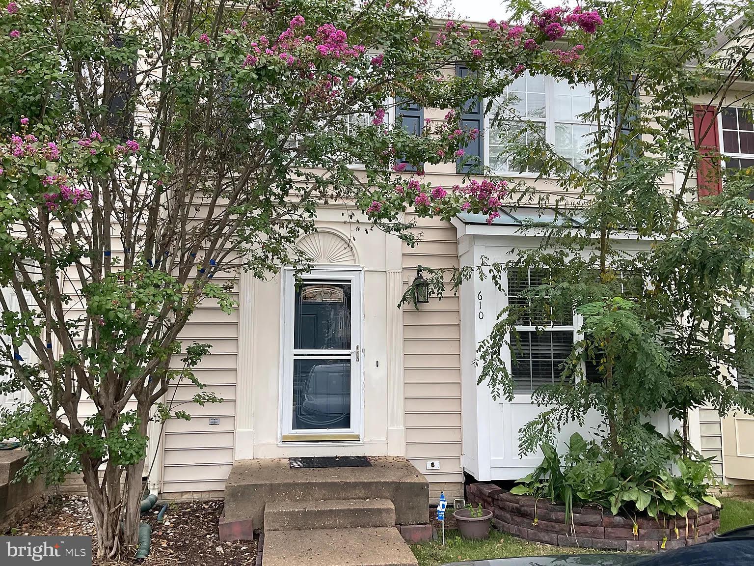 a view of a white house with a tree and flower plants