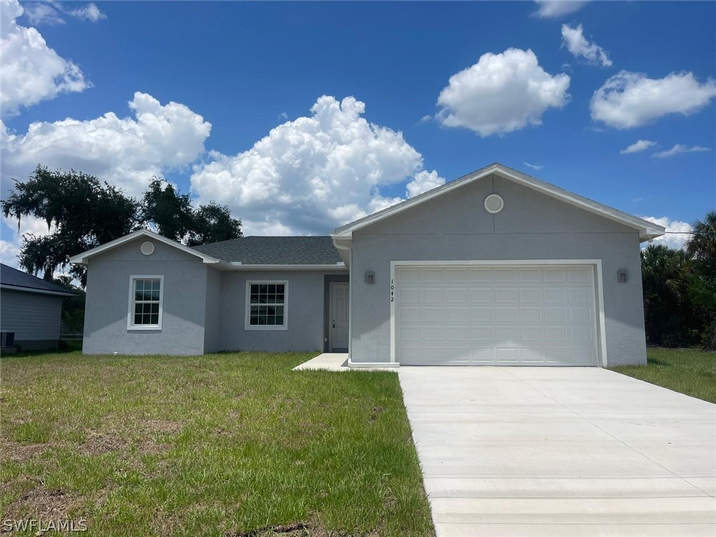 a front view of house with yard and trees in the background