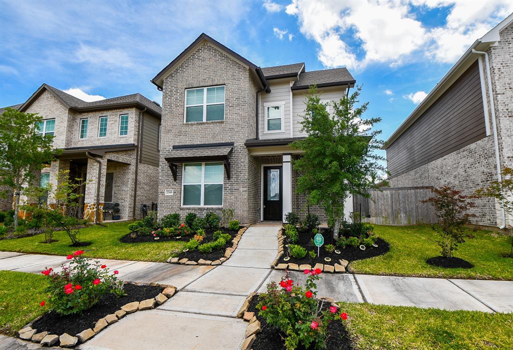 a front view of a house with a yard and flower plants