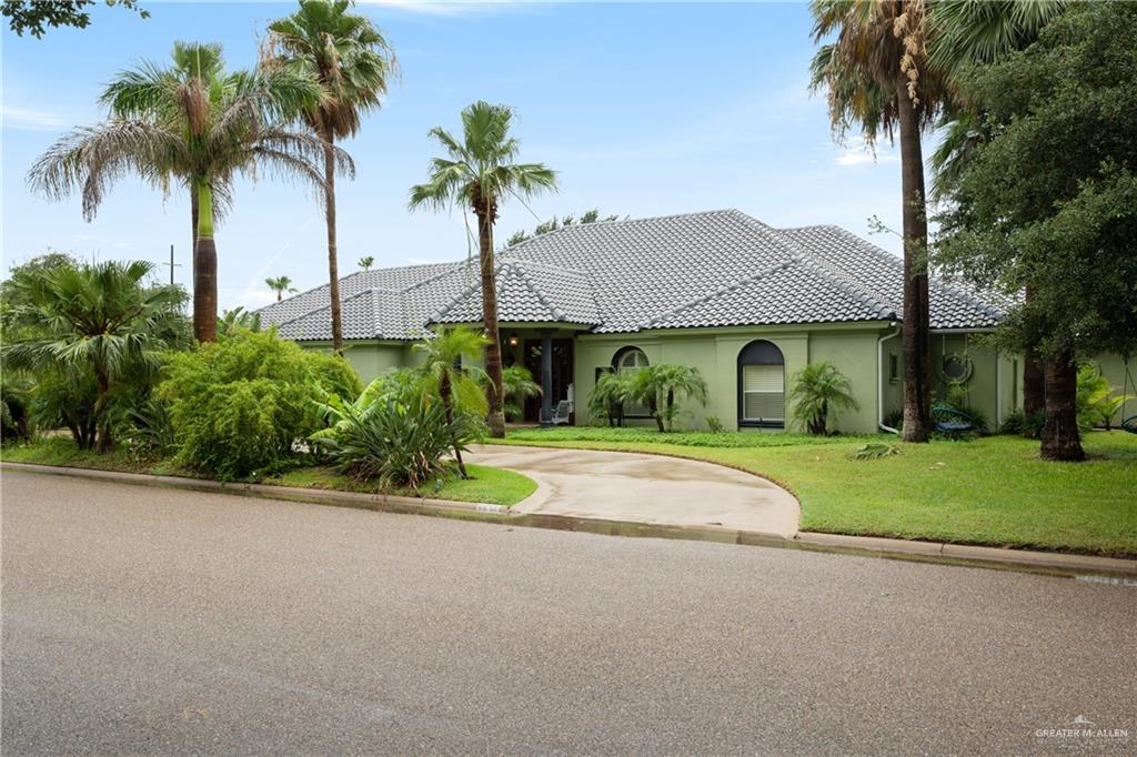 a front view of a house with a garden and trees