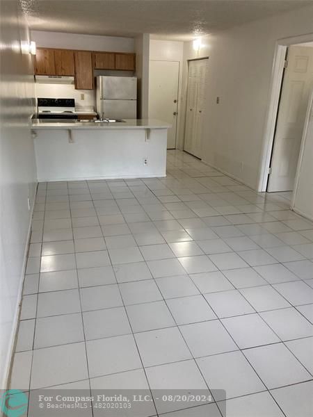 a view of a refrigerator in kitchen and an empty room