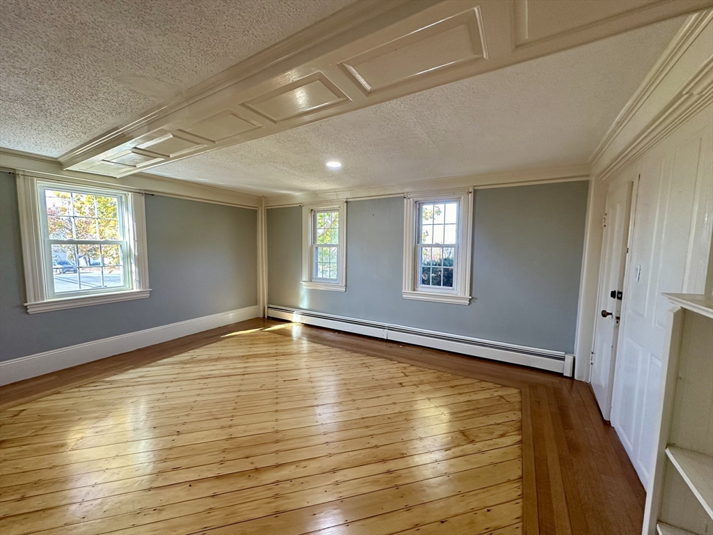 a view of an empty room with window and wooden floor