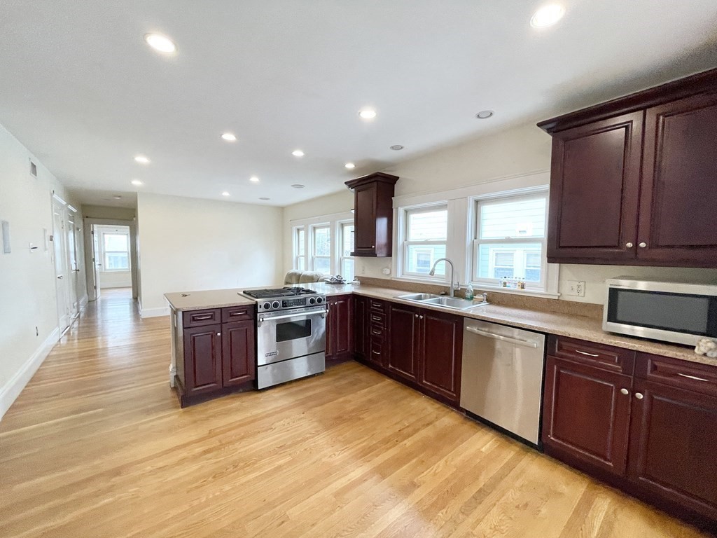 a large kitchen with stainless steel appliances granite countertop a large counter top a sink and wooden floors