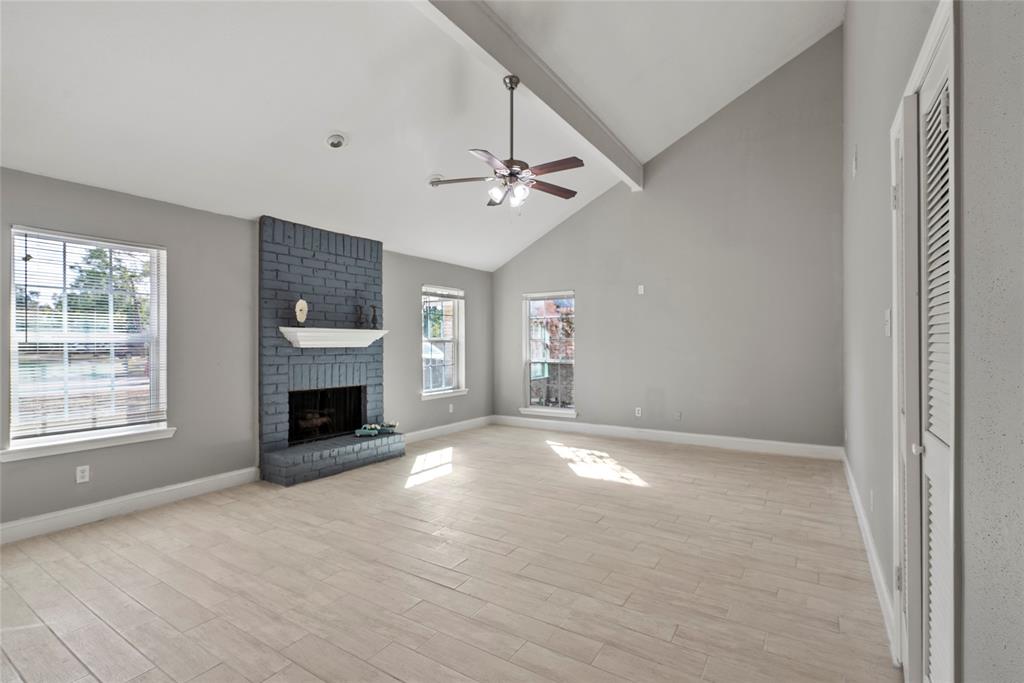 an empty room with windows and fireplace