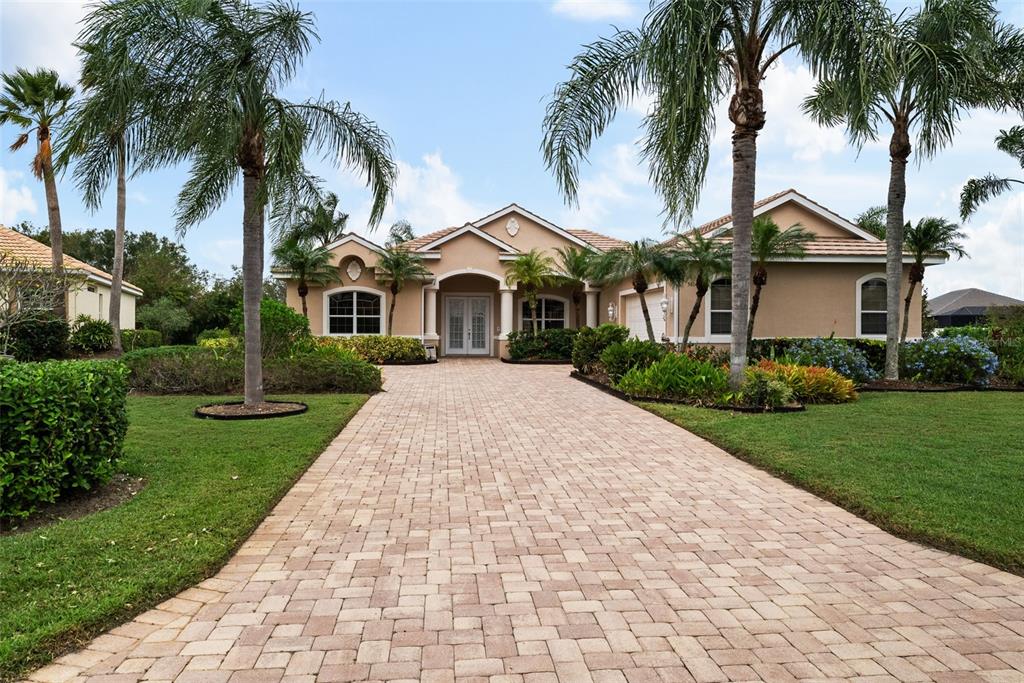 a front view of a house with a garden and palm trees