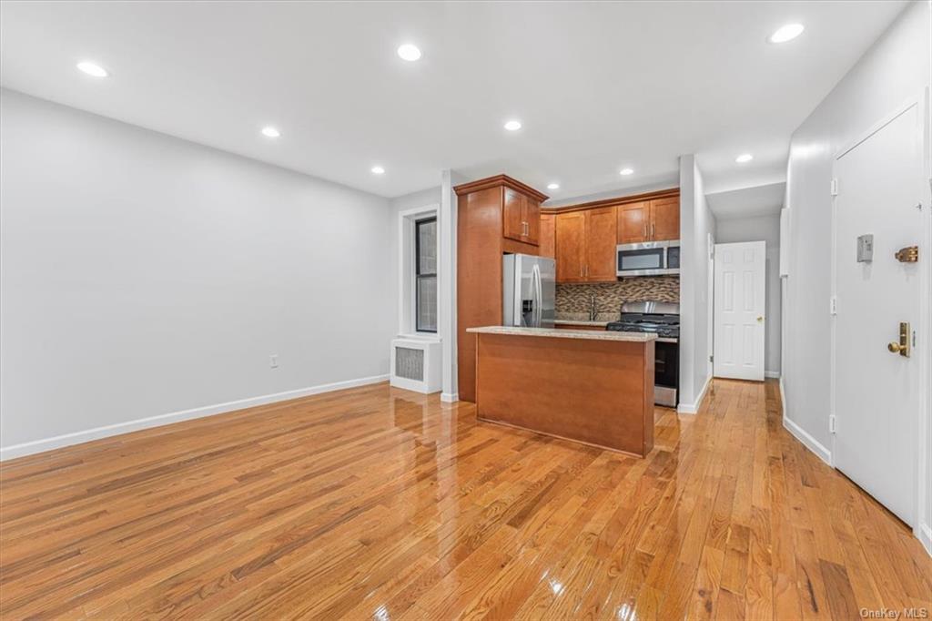 Kitchen with backsplash, a kitchen island, appliances with stainless steel finishes, and light wood-type flooring