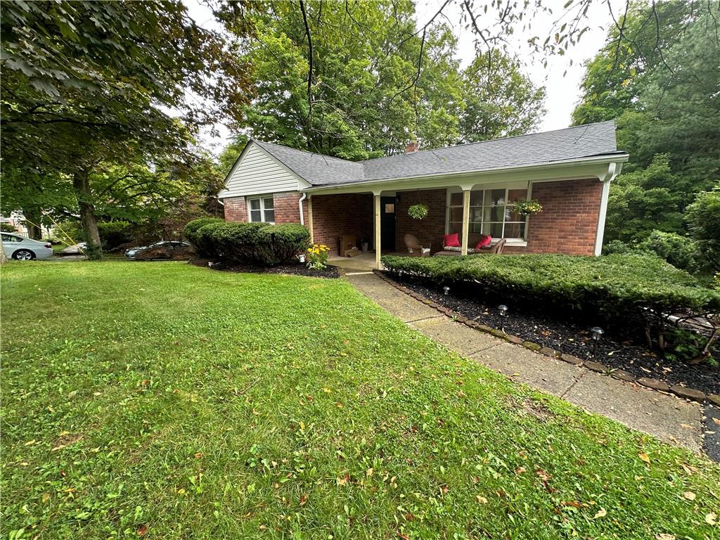 Ranch-style home featuring a front lawn and covered porch