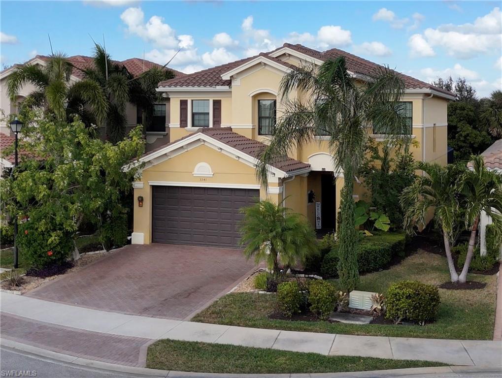 Grand Mediterranean-style entrance with an extended paver driveway, lush landscaping, and elegant architectural details, showcasing the pinnacle of Naples luxury living in Riverstone Naples Florida