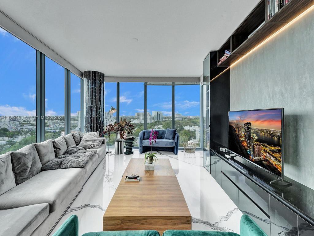 a living room with furniture tv and large windows