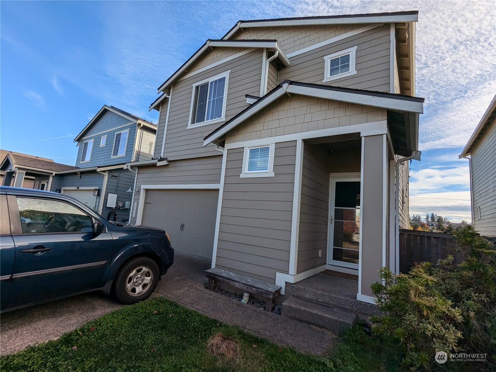 a view of a house with a small yard and parking space