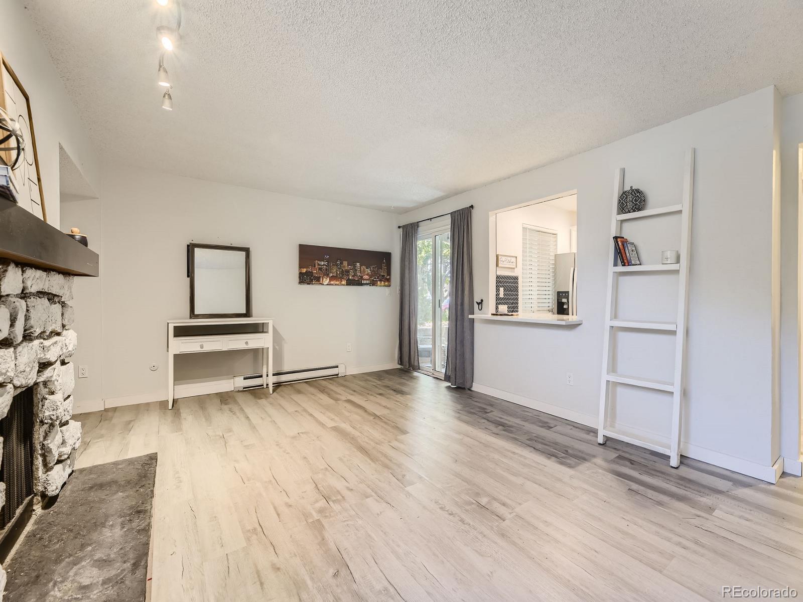 a view of empty room with wooden floor and kitchen