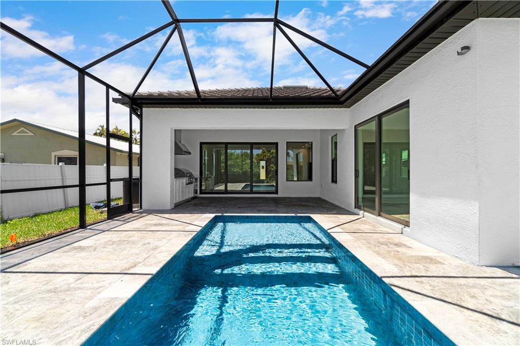 View of swimming pool with glass enclosure and a patio area