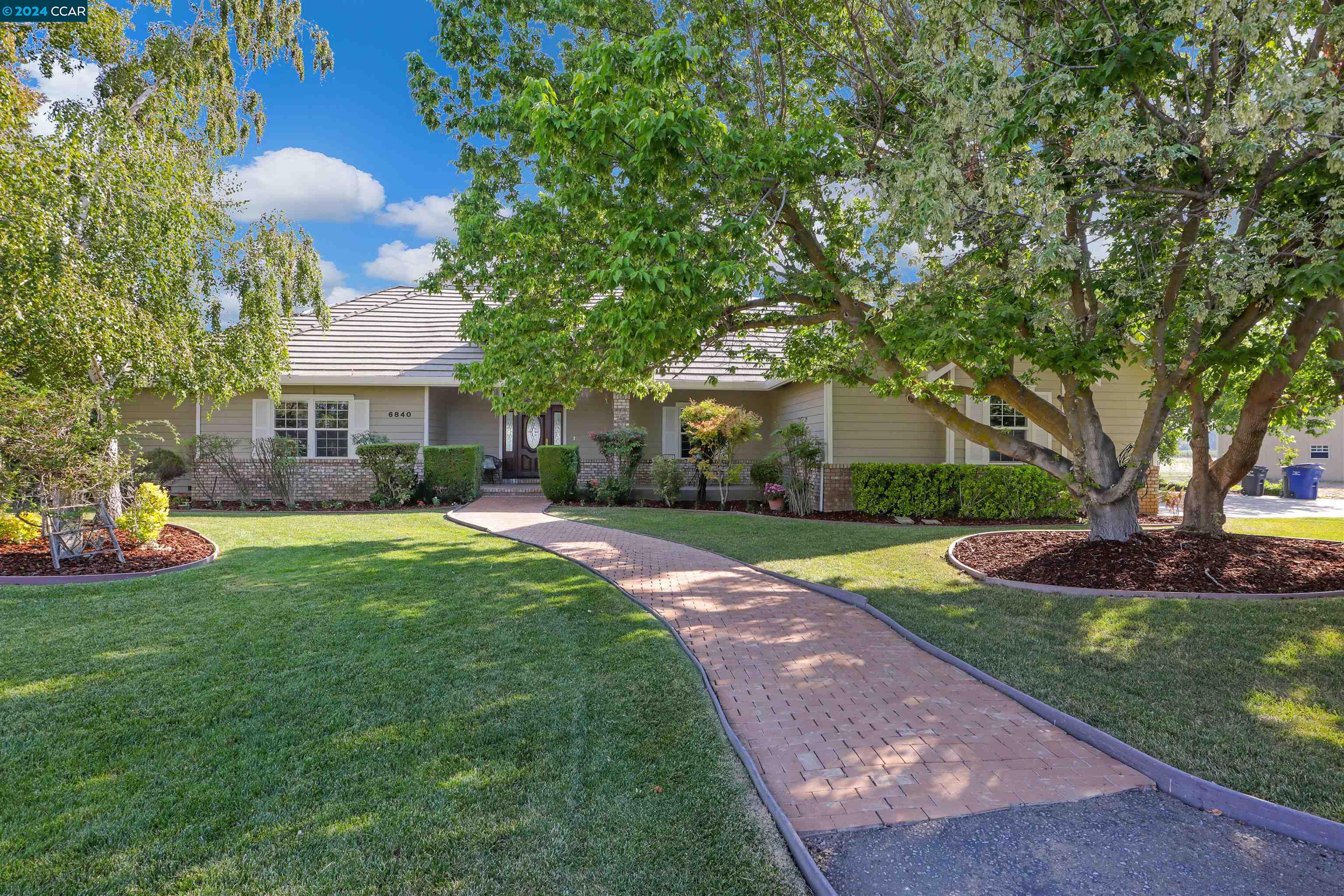 a front view of a house with garden and trees