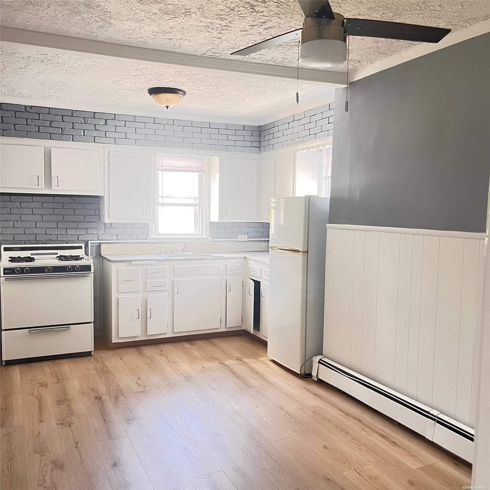 a kitchen with granite countertop a refrigerator a sink and white cabinets