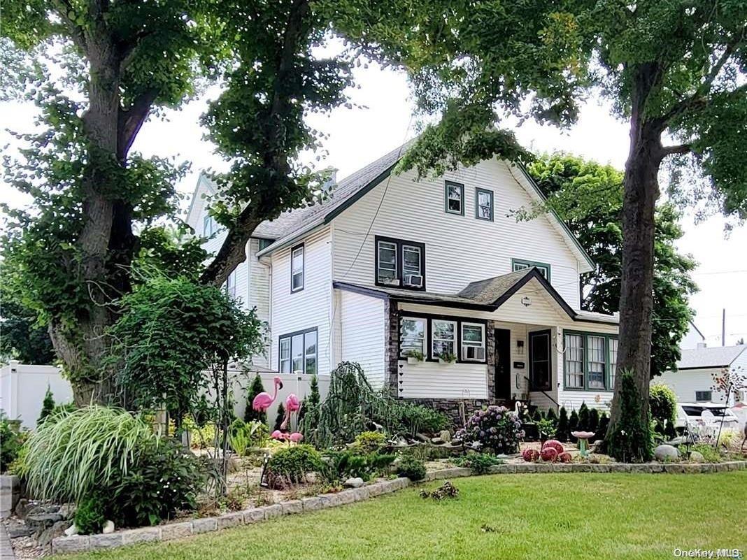 a front view of a house with a garden and trees