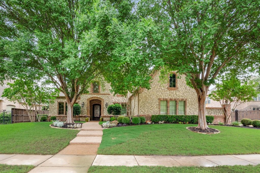 a white house with a big yard plants and large trees