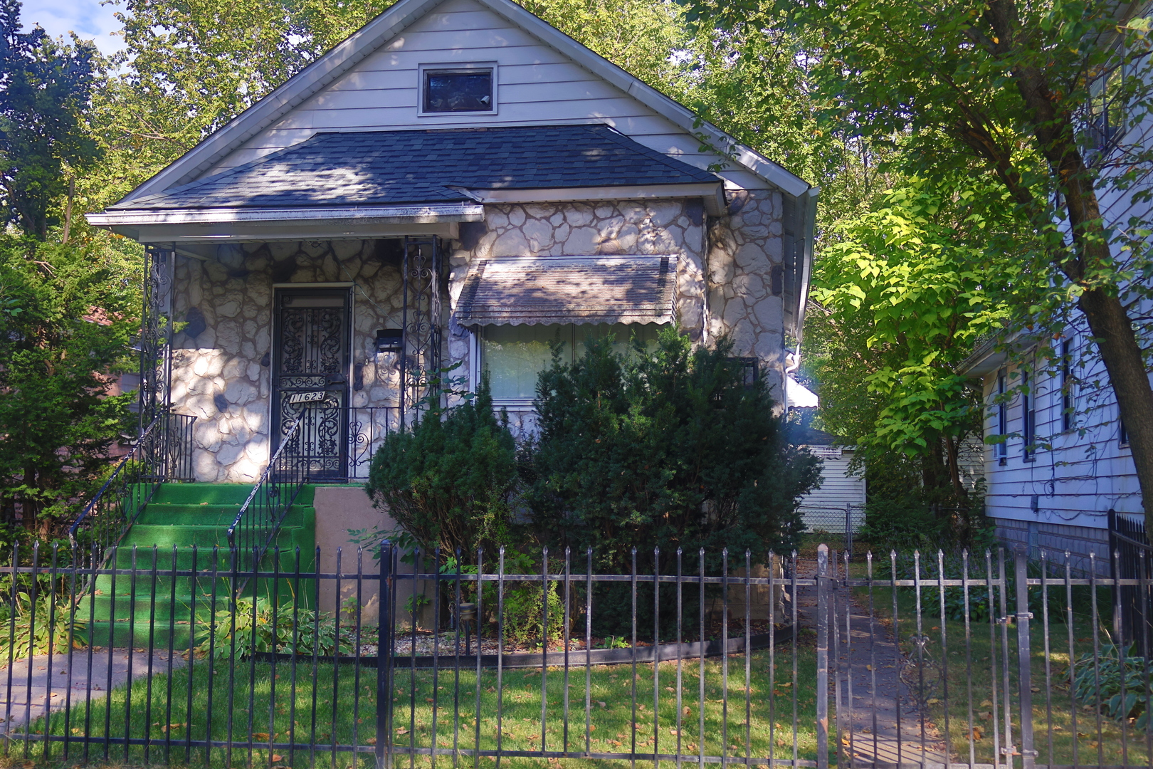 a view of a house with a small yard plants and a large tree