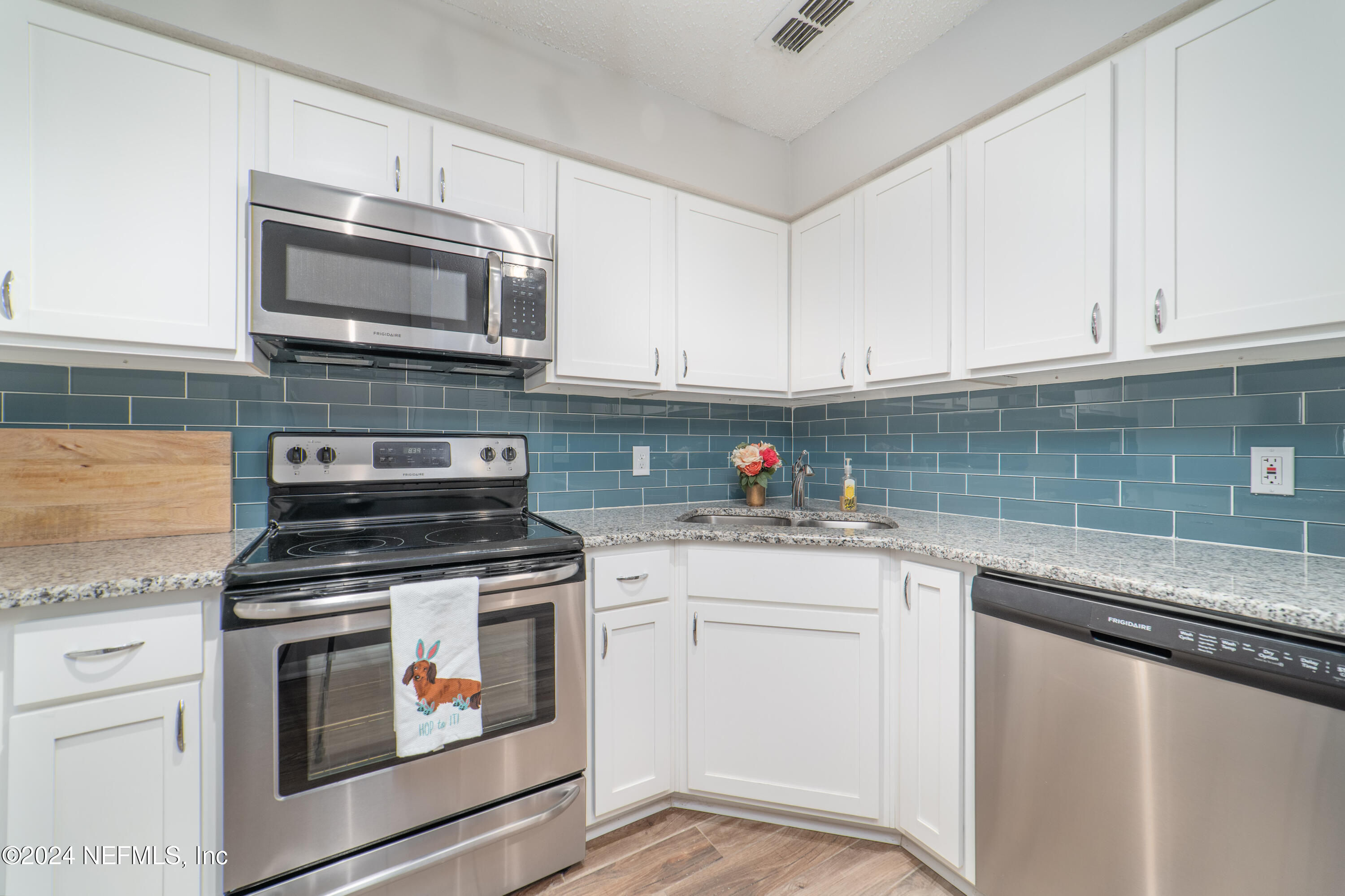 a kitchen with granite countertop white cabinets and stainless steel appliances