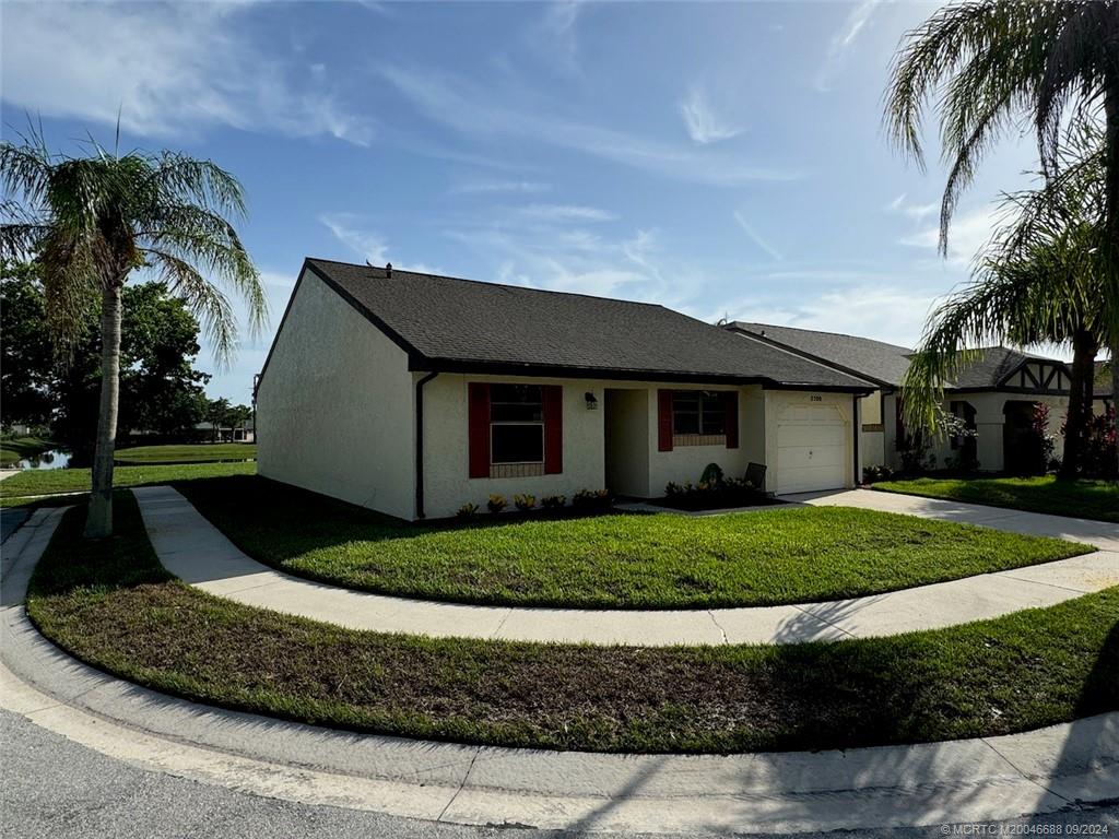 a front view of a house with a yard and potted plants