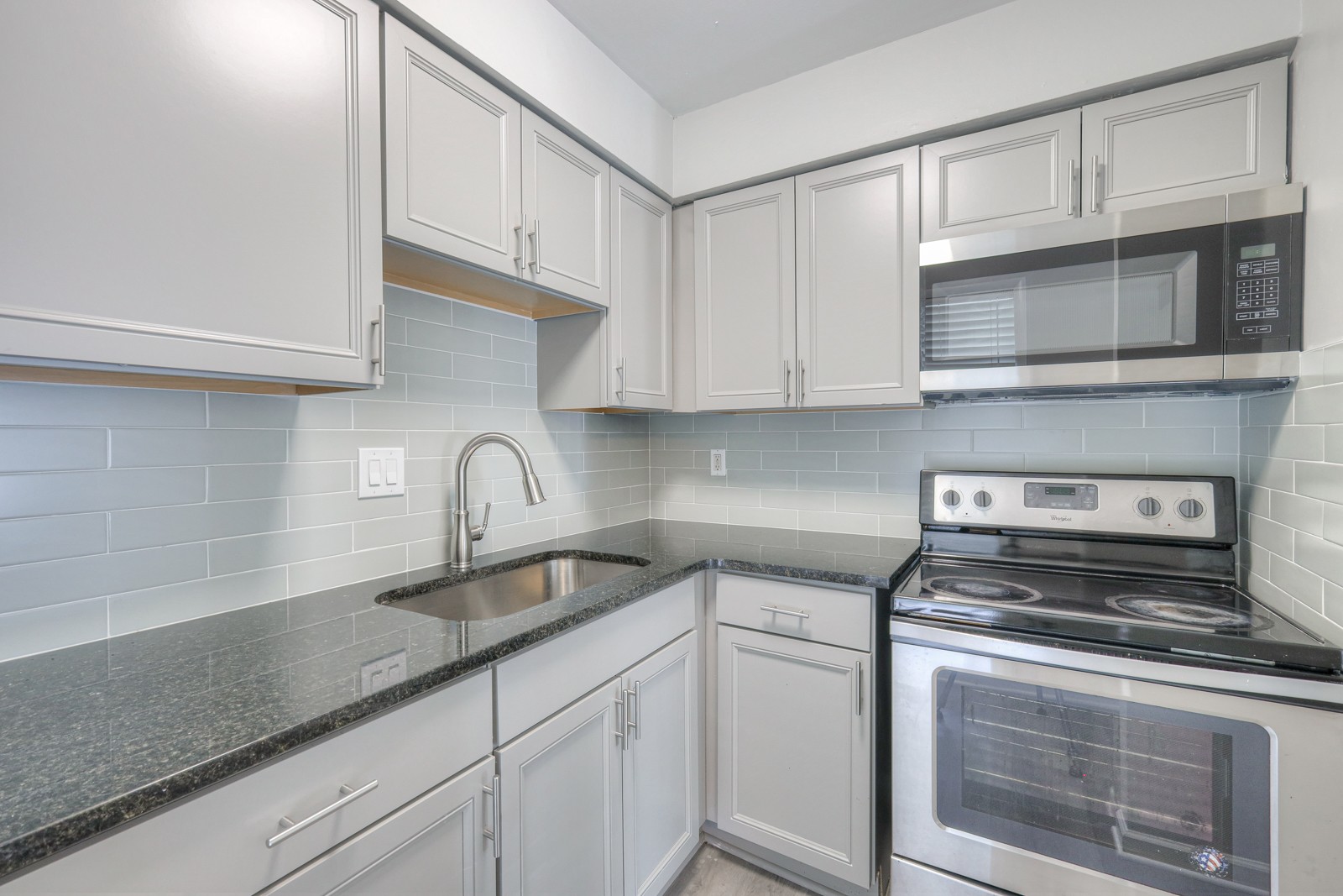 a kitchen with granite countertop white cabinets stainless steel appliances and sink