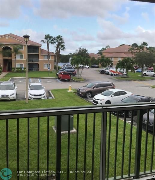 a balcony view with couple of cars parked in front of it