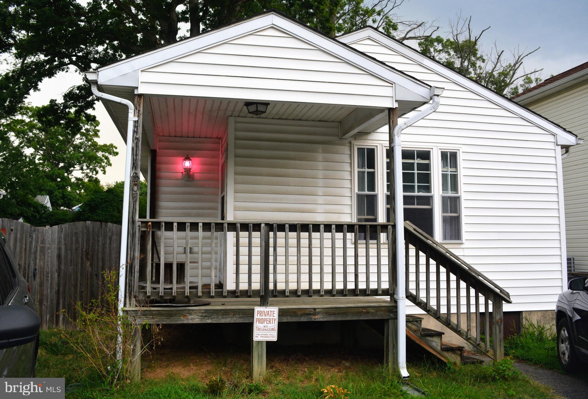 a view of a white house with a small yard and wooden fence