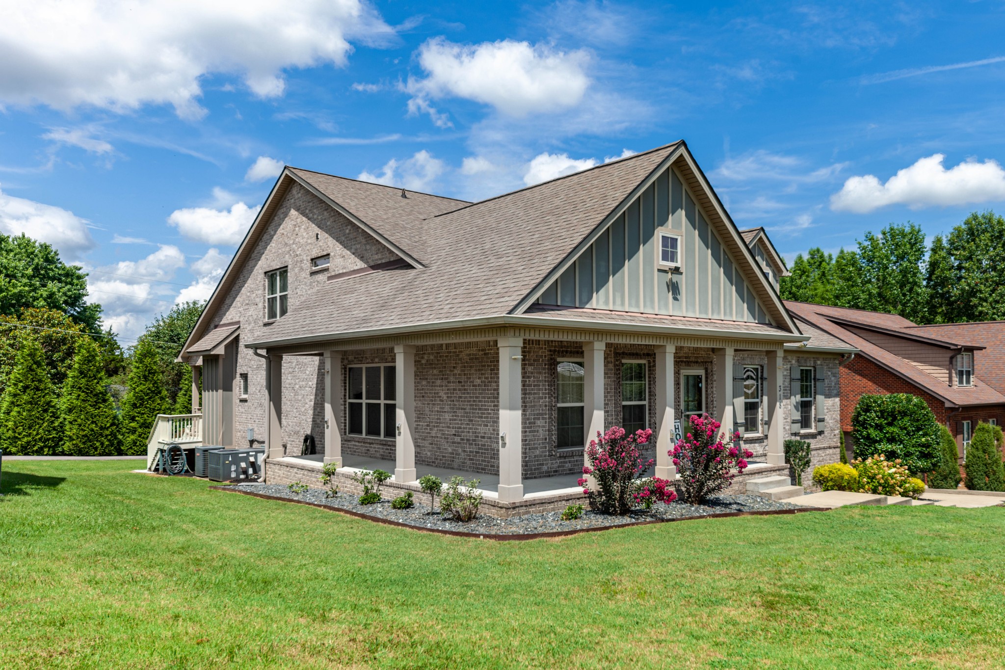 a view of a house with a yard potted plants and a large tree