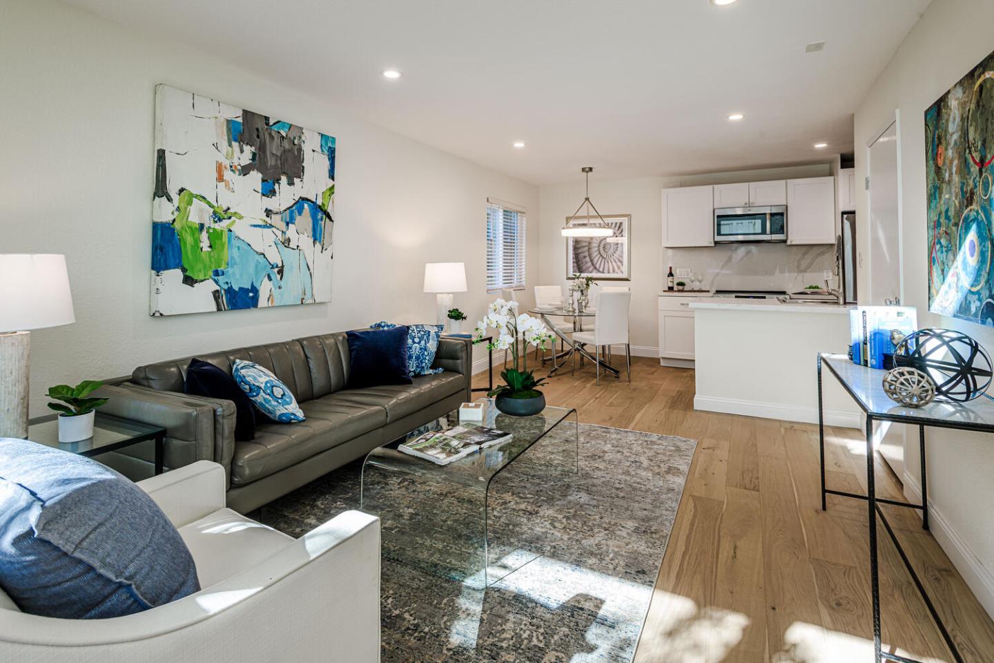 a living room with stainless steel appliances furniture and a kitchen view