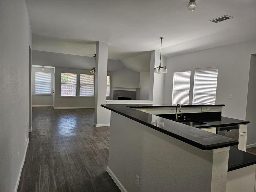 a kitchen with granite countertop a sink a counter top space and cabinets