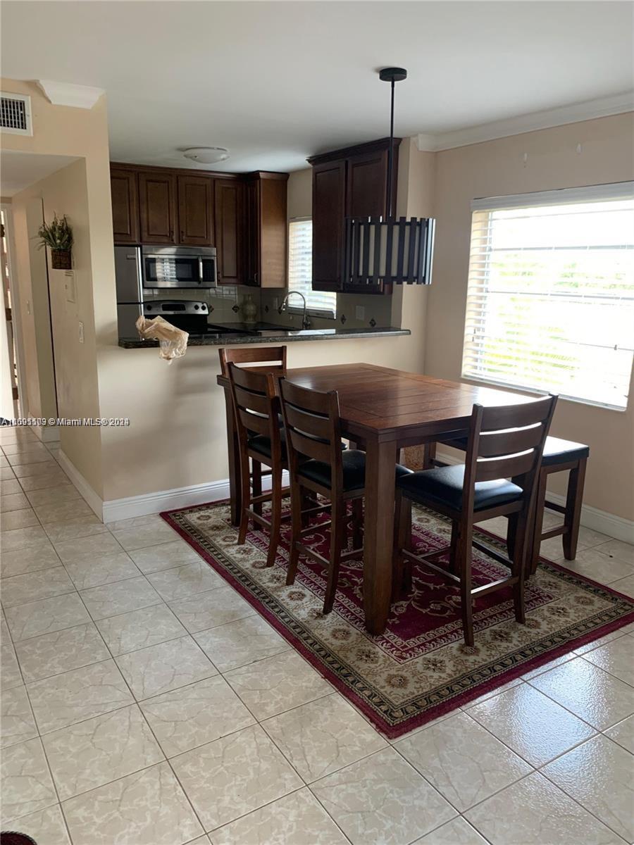 a kitchen with stainless steel appliances a dining table chairs microwave and sink