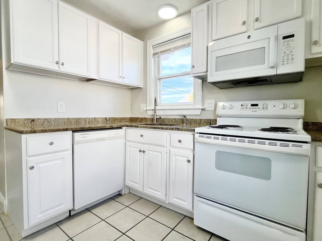 a kitchen with stainless steel appliances granite countertop white cabinets sink and a wooden floor