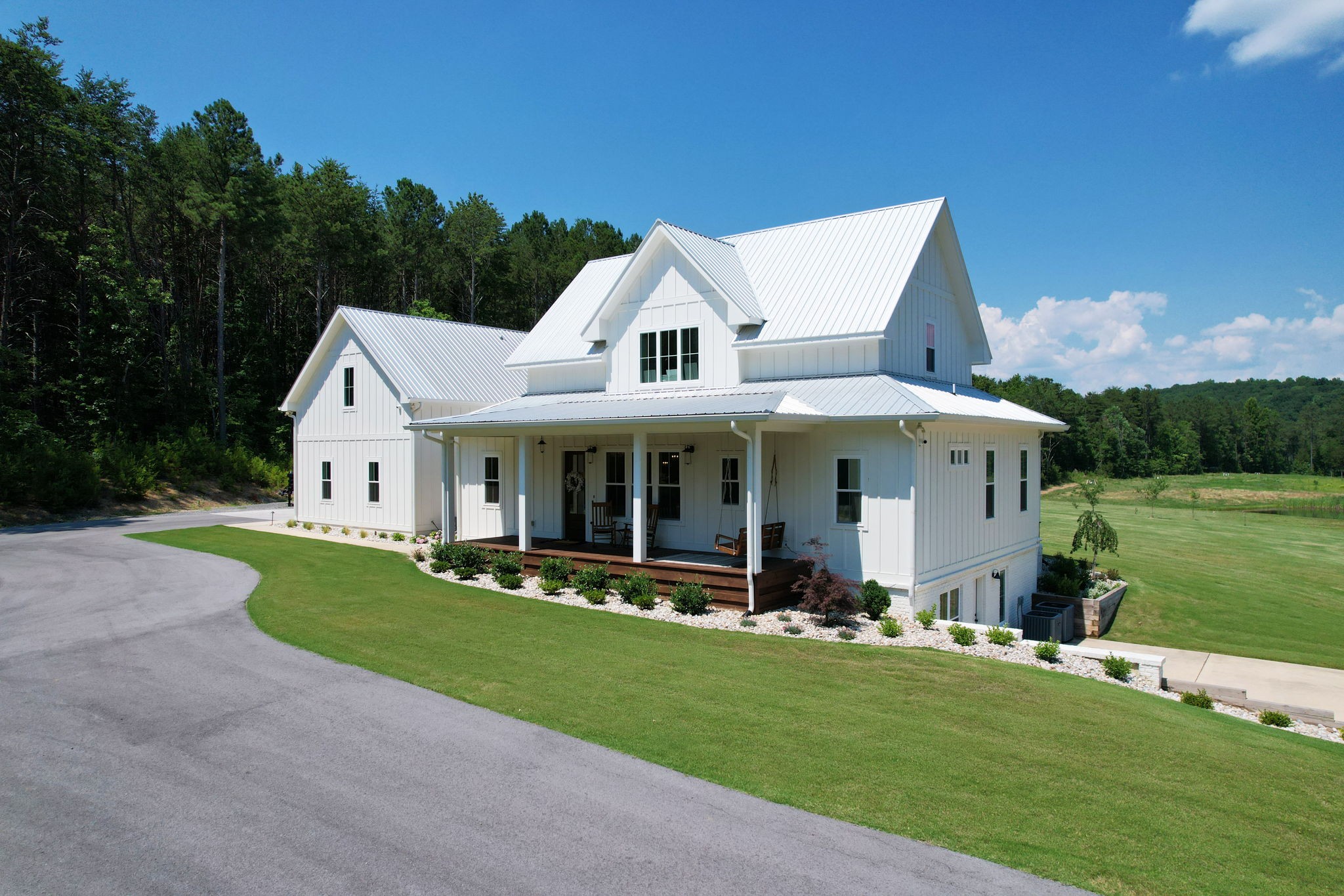 a view of a white house with a big yard and large trees