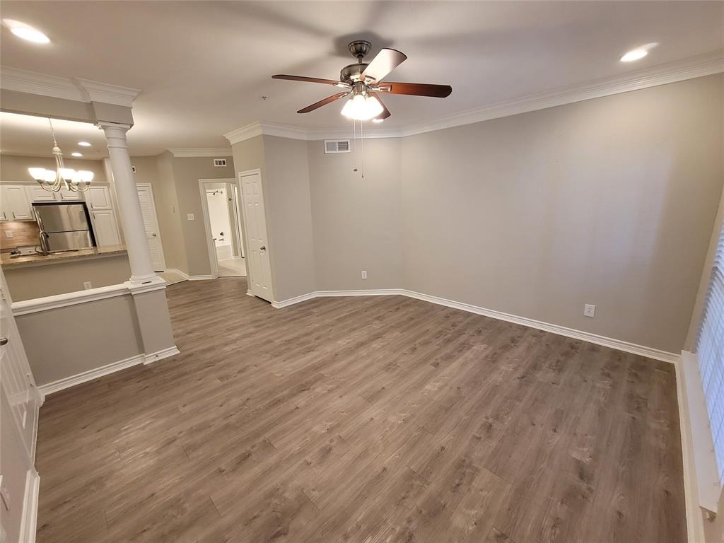 an empty room with wooden floor and a ceiling fan