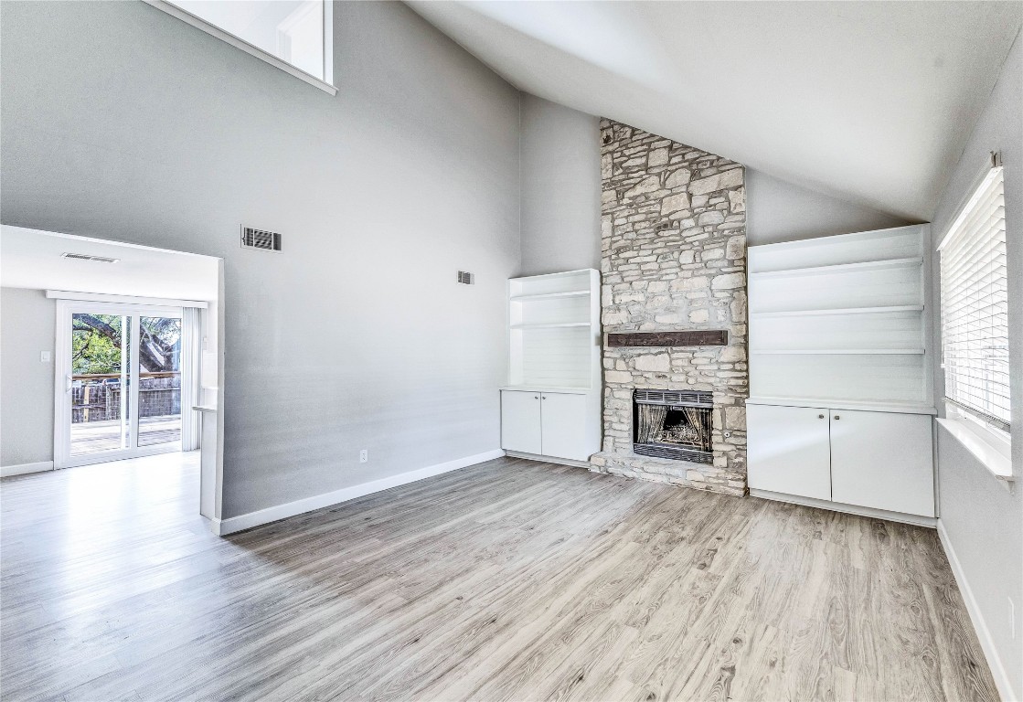 an empty room with wooden floor fireplace and windows