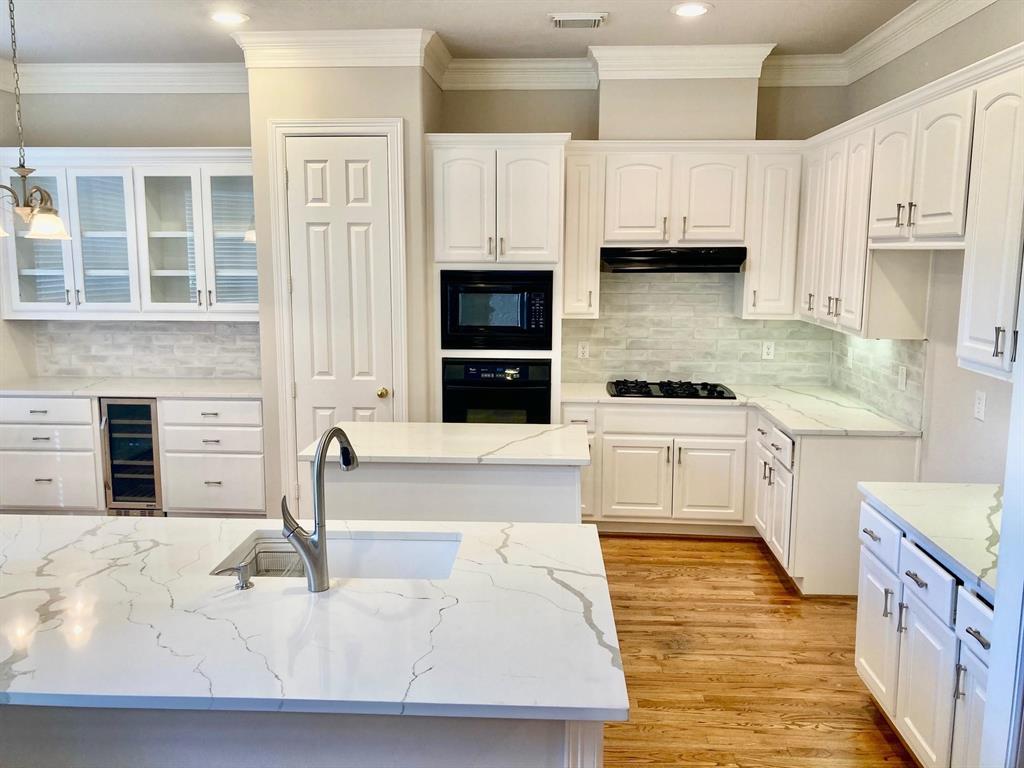 a kitchen with stainless steel appliances kitchen island granite countertop a stove a sink and white cabinets