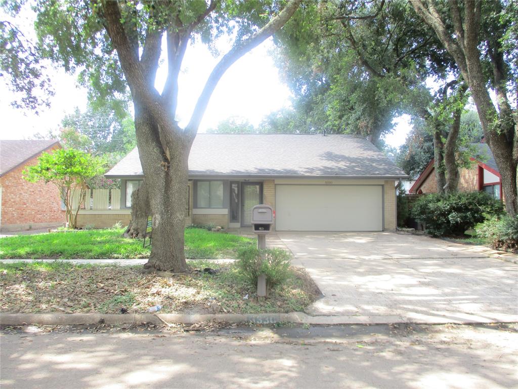 a view of a house with a yard and large tree