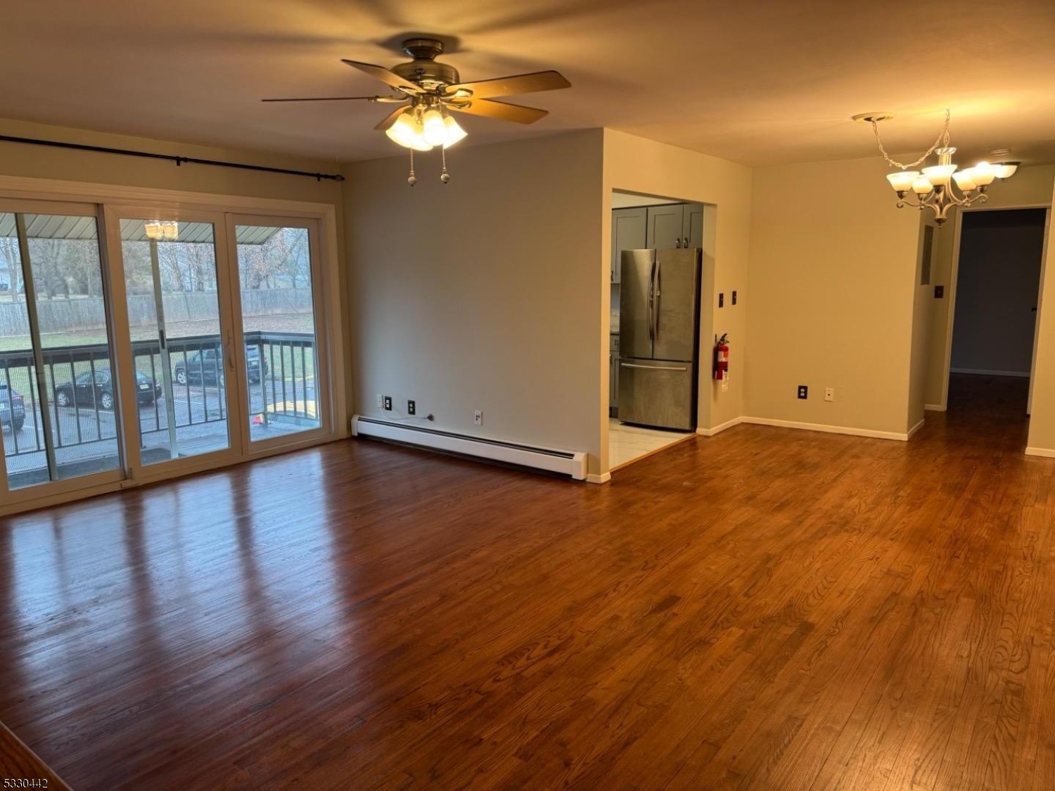 a view of an empty room with window chandelier fan and wooden floor